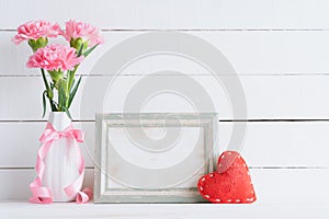 Valentines day and love concept. Pink carnation flower in vase with old vintage picture frame and red heart and on white