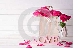 Valentines day and love concept. Pink roses in paper bag with Wooden letters forming word LOVE written on white wooden background