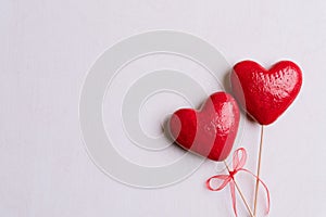 Valentines day and love concept. Two handmade red hearts with red ribbon on white wooden background