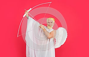 Valentines day. Love and romance. Smiling male angel aiming with bow and arrow. Valentine cupid in angel wings shooting