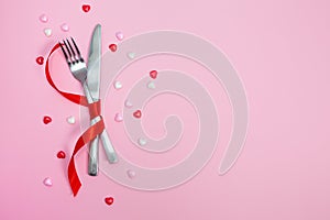 Valentines day meal background with red ribbon, hearts, fork, knife, white plate and napkin. Romantic holiday table