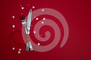 Valentines day meal background with red ribbon, hearts, fork, knife, white plate and napkin. Romantic holiday table