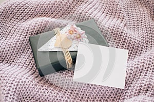 Valentines day mockup. gift box with empty white card on lilac knitted sweater. Black paper present box with heart, lace