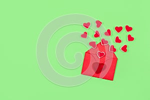 Valentines day pastel minimal creative background. Text Love is, red envelope many heart shape candies on green background.
