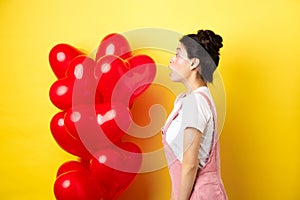 Valentines day and relationship concept. Profile of surprised asian girl staring left at logo, standing near heart