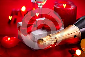 Valentines Day romantic dinner. Date. Champagne, candles and gift box over holiday red background