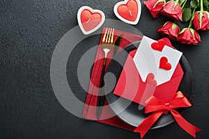 Valentines day romantic table setting. Empty closeup of red roses, wine, candles, dinner black plate, knife, fork and decorative