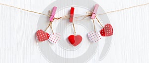 Valentines Day. Sewed pillow hearts row border on red and white clothespins at rustic white wood planks.