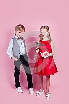 Valentines day surprise. Little boy in love giving cute girl red rose