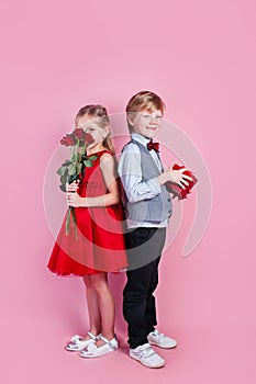 Valentines day surprise. Little boy in love giving cute girl red rose