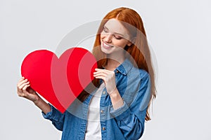 Valentines day, sympathy and relationship concept. Lovely creative cute redhead girl made red big heart for gift