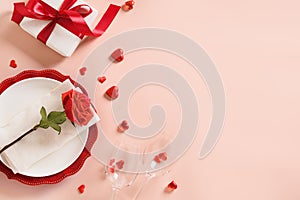 Valentines day table place setting with gift, a bottle of red wine, roses, hearts.