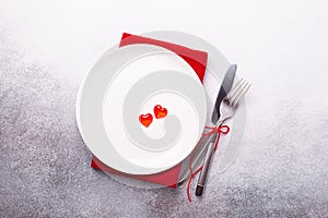 Valentines day table place setting with red hearts and silverware on stone background. Top view. Valentine`s card