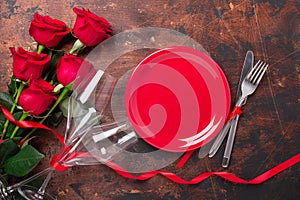 Valentines day table setting empty plate, red roses and champagne glasses on wooden background. Top view. Valentine`s greeting