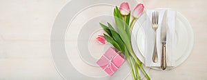 Valentines day table setting with pink tulips and a gift on white wooden background. Top view, copy space, banner