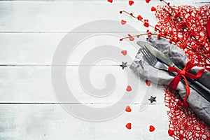 Valentines day table setting with plate, knife, fork, red ribbon and hearts