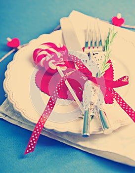 Valentines day table setting with plate, knife, fork, red ribbon