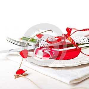 Valentines day table setting with plate, knife, fork, red ribbon