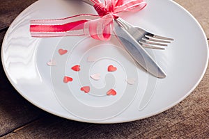 Valentines day table setting with plate, knife, fork, red ribbon