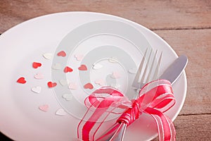 Valentines day table setting with plate, knife, fork, red ribbon