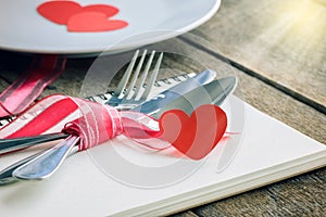 Valentines day table setting with plate, knife, fork, red ribbon