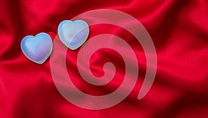 Valentines day. Top view of light blue glass hearts, red silk background