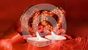 Valentines day, two candles burning in front of hearts, closeup