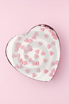 Valentines Day white cake with sugar pink hearts on pink background