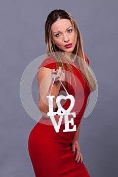 Valentines Day. Woman wearing red dress holding sign love symbol