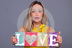 Valentines Day. Woman wearing yellow dress holding sign love symbol