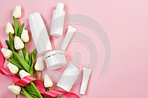 Valentines Day and Womens Day, mother`s day concept. Empty white tubes and bottles with white tulips on a pink background