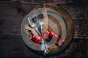 Valentines dinner setting with vintage silverware, dinner plate and red ribbon on wooden table. Valentine day background frame for