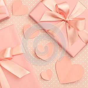 Valentines or Mothers day present box with bow ribbon decorated coral small hearts top view on living coral color background.
