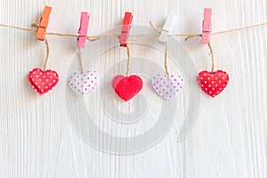 Valentineâ€™s Day. Sewed pillow hearts row border on red, pink and white clothespins at rustic white wood planks