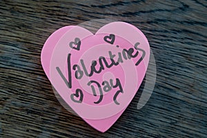 Valentineâ€™s Day wrote text on pink love heart with drawn hearts. On rustic wooden background. Love Valentines concept