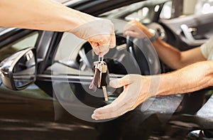 Valet parking worker giving key to man sitting in car