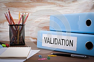 Validation, Office Binder on Wooden Desk. On the table colored pencils, pen, notebook paper