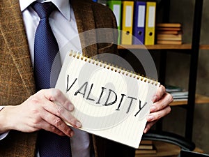 Validity concept. A man in a suit holds a handwritten lettering.