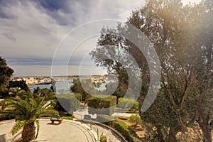 Valletta city harbor area and an outdoor park at Malta, with many historic buildings along the coastline