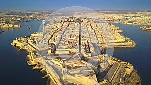 Valletta, Malta - 4K drone flying above Valletta with Breakwater, Grand Harbor, Floriana, Manoel Island at sunrise