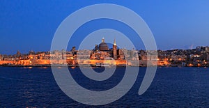 Valletta, Malta in the evening. Panoramic view of illuminated historic island and the dome of Carmelite Church and St Paul`s tower