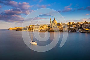 Valletta, Malta - St.Paul`s Cathedral in golden hour at Malta`s capital city Valletta with sailboat