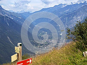 In the valley of the Alps you can see the inhabited locality. Pointers show directions for hiking trails