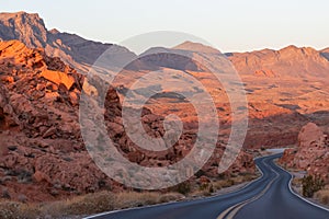 Valley of Fire - Panoramic sunrise view of endless empty road leading to red Aztec Sandstone Rock formations in Mojave desert