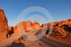 Valley of Fire - Panoramic sunrise view of endless empty road leading to red Aztec Sandstone Rock formations in Mojave desert