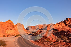 Valley of Fire - Panoramic sunrise view of endless empty road leading to red Aztec Sandstone Rock formations in Mojave desert