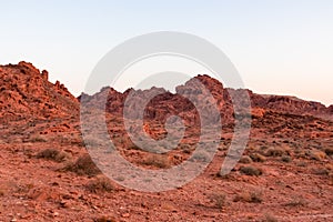 Valley of Fire - Panoramic sunrise view of red and orange Aztec Sandstone Rock formations and desert vegetation, Nevada