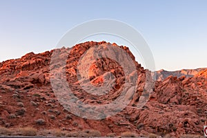 Valley of Fire - Panoramic sunrise view of red and orange Aztec Sandstone Rock formations and desert vegetation, Nevada