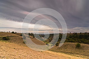 Valley between small hills under dark clouds