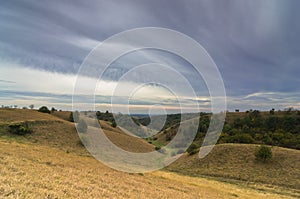 Valley between small hills under dark clouds